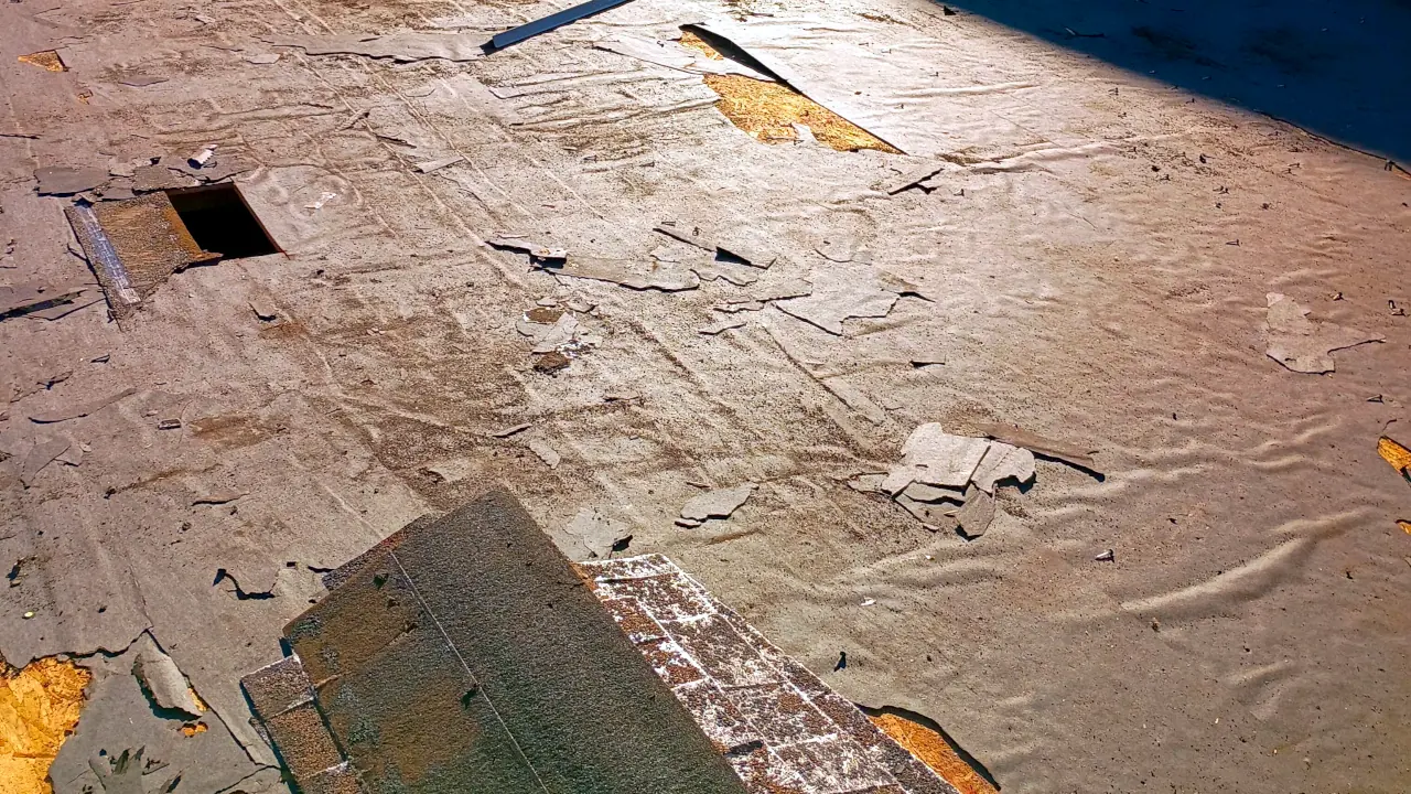 A close-up view of a roof in Tucson, AZ showing damaged sheets with holes and chipped areas that need repair.